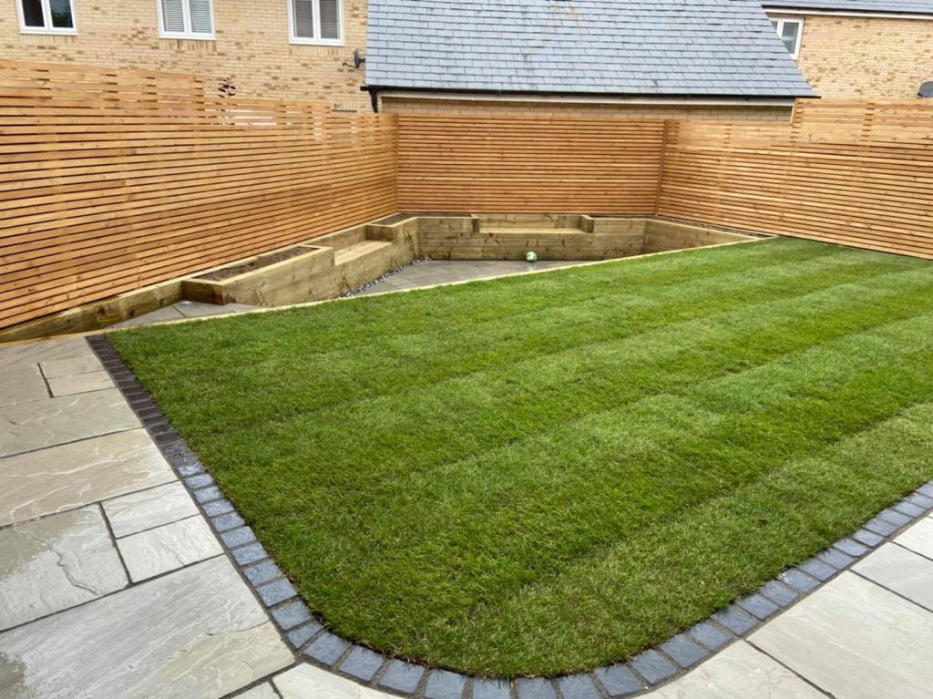 Fencing, plant bed, lawn and natural stone patio