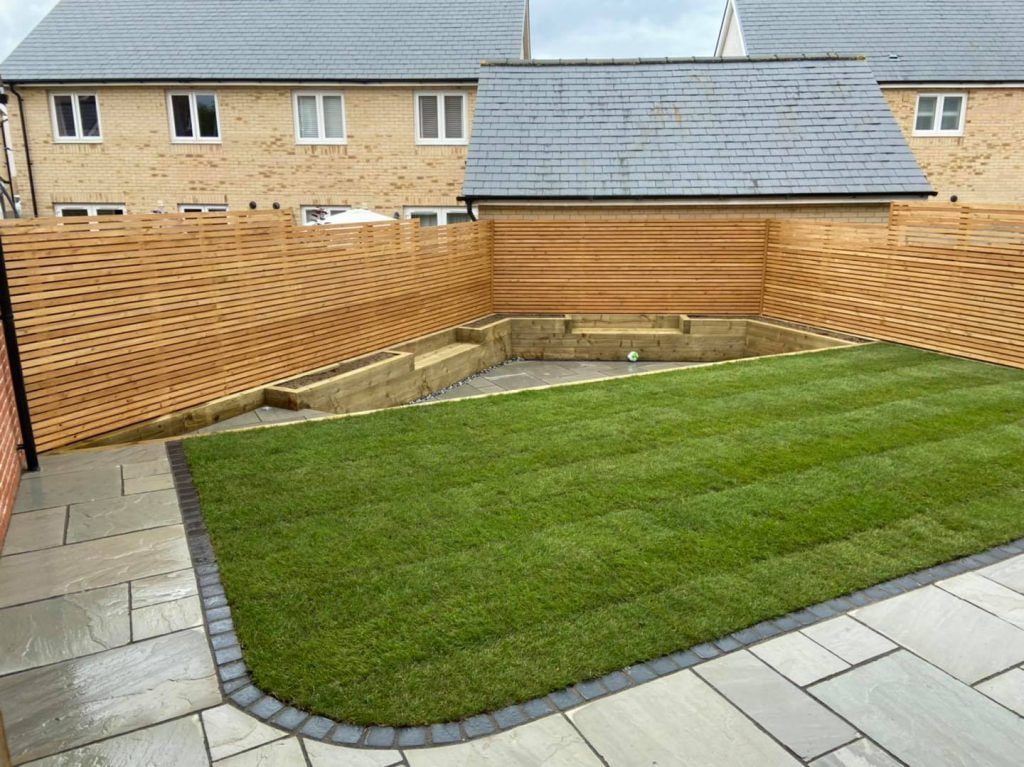 Fencing, plant bed, lawn and natural stone patio