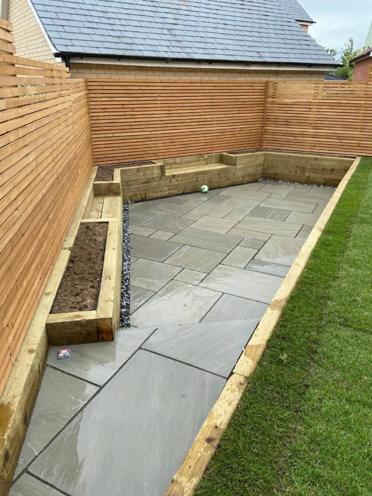 Stone patio, fence, plant bed and lawn