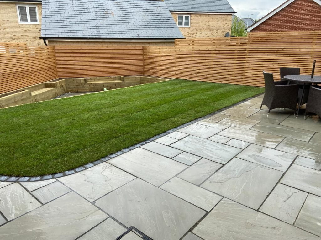 Stone patio, fence, plant bed and lawn