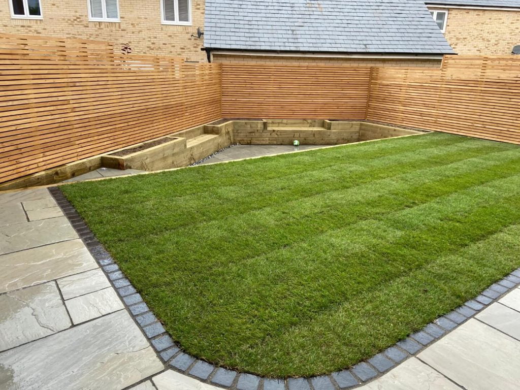Stone patio, fence, plant bed and lawn